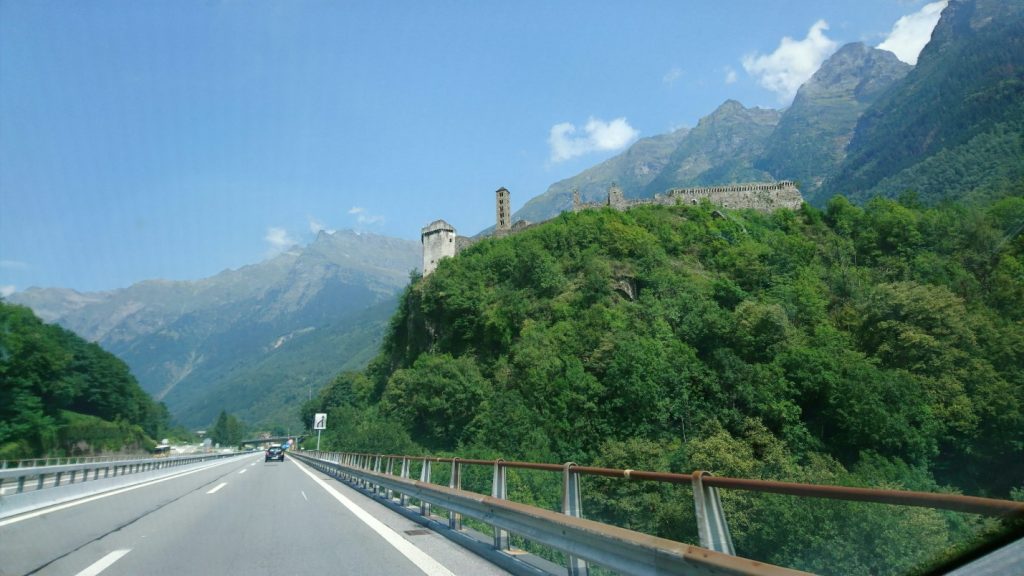 gray concrete bridge near green mountain during daytime